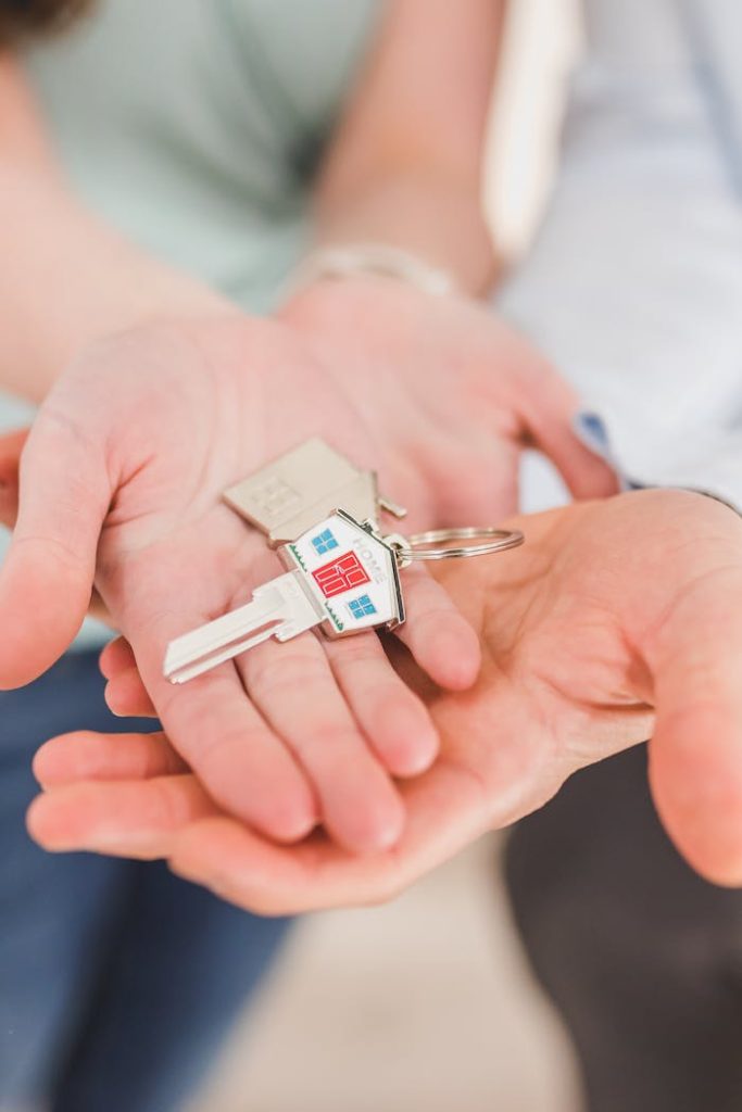 people-holding-a-house-shaped-key-8292770 Close-up of hands holding a key with a house-shaped keychain, symbolizing new beginnings.