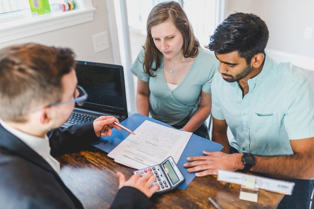 real-estate-agent-in-black-coat-discussing-an-ownership-agreement-to-a-couple-inside-the-office-8293651 Young couple meeting with real estate agent to discuss property purchase.