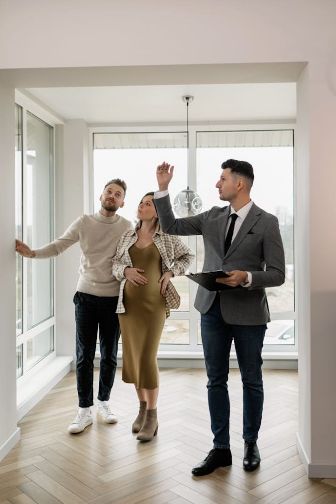 real-estate-agent-showing-property-to-a-couple-7641856 A couple tours a modern home with a real estate agent, exploring their potential new living space.